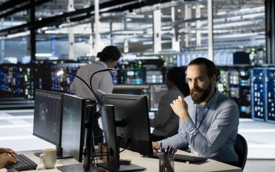 Technician using PC in data center to update server tech, configuring equipment using software tools. Server room employee reviewing hardware analytics, ensuring reliable network operations